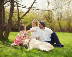Family sitting in park with dog